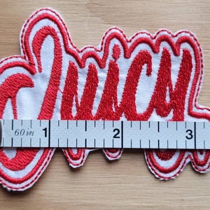 May include: Red embroidered patch with the word "Juicy" in white outlined letters. The patch is about 3 inches wide and is measured with a ruler.