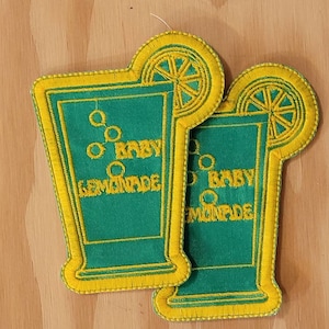 Pode incluir: Dois patches bordados verdes e amarelos com um copo de limonada e o texto "Baby Lemonade" em cada um.