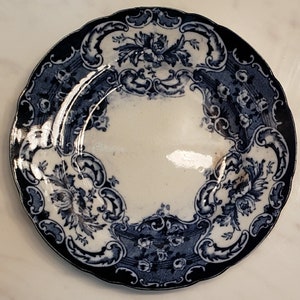May include: A blue and white porcelain plate with a floral design. The plate has a scalloped edge and a raised rim.
