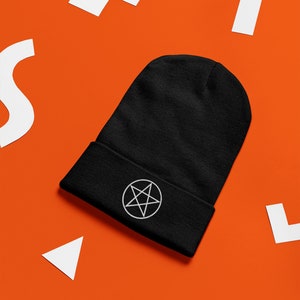 May include: Black beanie with a white pentagram embroidered on the front. The beanie is on a bright orange background.