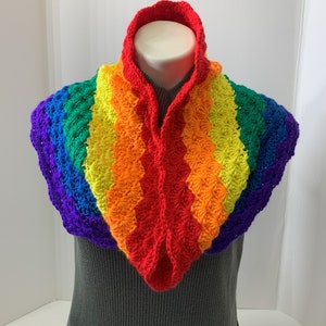 May include: A rainbow crocheted cowl with a scalloped edge. The cowl is made in the colors of the rainbow, starting with purple and ending with red.