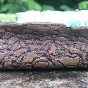 May include: A ceramic dish with a brown, textured exterior and a light blue interior. The dish has a unique, organic shape.