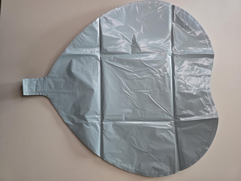 Op de afbeelding: Een grote, lichtblauwe ballon in een druppelvorm, gemaakt van een gekreukeld, glanzend materiaal. De ballon heeft een rechthoekig lipje dat zich vanaf &eacute;&eacute;n uiteinde uitstrekt en is verdeeld in secties door verticale en horizontale naden.