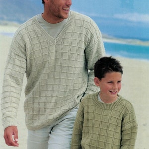 Op de afbeelding: Twee mensen dragen beige en groene gebreide truien met een V-hals en een ronde hals. De truien hebben een textuurpatroon.