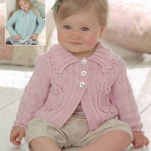 Op de afbeelding: Een roze gebreide cardigan met een witte knoopsluiting en een witte kraag. De cardigan heeft een bloemenpatroon en wordt gedragen door een klein kind.