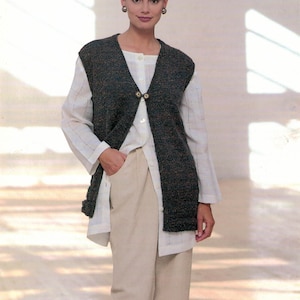 May include: A brown and green knitted waistcoat with a V-neck and button fastening. The waistcoat is worn over a white button-down shirt and beige trousers.