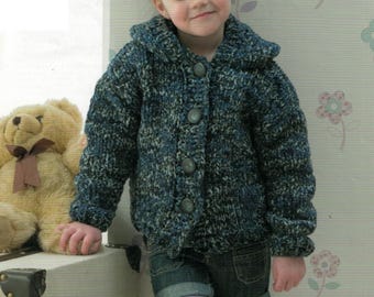Könnte beinhalten: Ein Kind trägt eine blau-graue Strickjacke mit großen Knöpfen. Die Strickjacke wird mit Jeansshorts und lila Strumpfhosen kombiniert. Ein Teddybär und ein weißer Koffer befinden sich im Hintergrund.