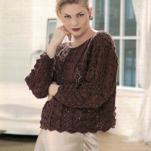 May include: A brown knitted jumper with a delicate lace pattern. The jumper has a round neckline and long sleeves.