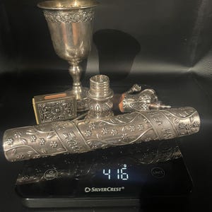 Może przedstawiać: Asortyment antycznych srebrnych przedmiotów, w tym kielich, małe pudełko i dekoracyjna tuba, jest prezentowany na wadze cyfrowej. Waga wskazuje 416 gramów. Przedmioty są misternie zdobione wzorami kwiatowymi.