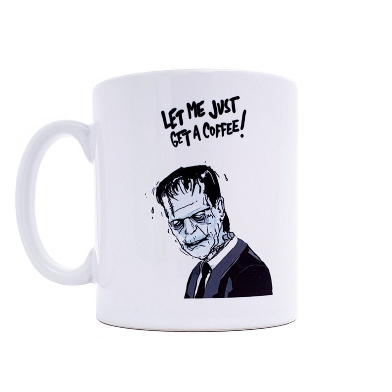 May include: White ceramic coffee mug with a black and white illustration of Frankenstein's monster. The text "Let me just get a coffee!" is printed on the mug.