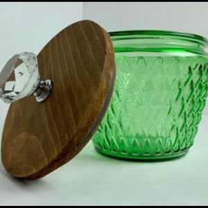 Könnte beinhalten: Ein grünes Glasgefäß mit einem strukturierten Rautenmuster, kombiniert mit einem Holzdeckel. Der Deckel hat einen klaren, facettierten Kristallknopf. Das Gefäß ist geöffnet.