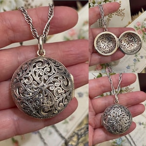 Peut inclure: Pendentif locket en filigrane argenté sur une chaîne argentée. Le locket rond présente un design ajouré complexe. Le locket s'ouvre pour révéler un intérieur détaillé. La chaîne est de style corde torsadée.