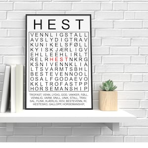 Puede incluir: Una impresión en blanco y negro enmarcada con la palabra "HEST" en la parte superior. Debajo, una cuadrícula de palabras, con "HEST" en rojo. La parte inferior de la impresión tiene una lista de palabras. Una pequeña suculenta en una maceta de madera está en un estante blanco.