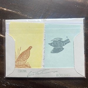 May include: Block prints featuring two bird illustrations. One print is yellow with a brown bird in grass, the other is light blue with a gray bird in flight. The package reads "Original" and "Block Prints".