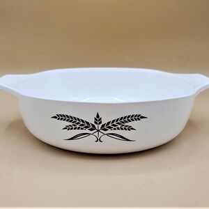 Puede incluir: Plato para hornear de cerámica blanca con un diseño de trigo negro. El plato tiene dos asas.