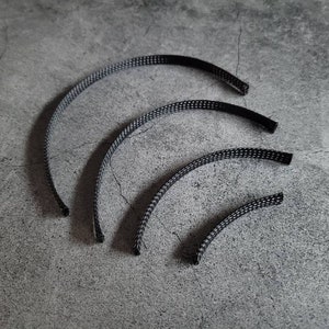 May include: Four black braided cable sleeves of different sizes, arranged in a semi-circle on a gray textured surface.