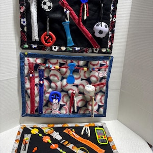 May include: A set of three sensory activity boards with sports themes. The top board has soccer balls and zippers. The middle board features baseballs and various tactile elements. The bottom board has basketballs and a toy phone.