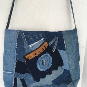 May include: A blue denim tote bag with a patchwork design. The bag has a long strap and is made from different pieces of denim fabric.