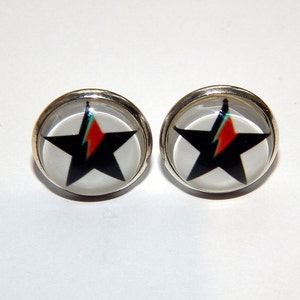 Op de afbeelding: Een paar zilveren oorbel studs met een zwarte ster en een rode, oranje en groene bliksemontwerp.