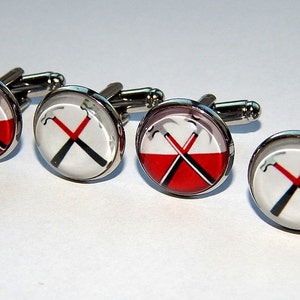 Può includere: Set di quattro gemelli d'argento con un design circolare rosso e bianco che presenta un'immagine in bianco e nero di martelli incrociati.