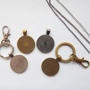K&ouml;nnte beinhalten: F&uuml;nf runde Metallanh&auml;nger mit einem dekorativen Muster. Die Anh&auml;nger sind in verschiedenen Gold- und Silbert&ouml;nen gehalten. Zwei der Anh&auml;nger sind an einem silbernen Schl&uuml;sselanh&auml;nger mit einem silbernen Verschluss befestigt. Die anderen drei Anh&auml;nger sind an einer silbernen Kette befestigt.