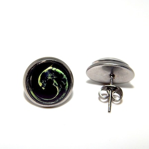 May include: A pair of silver stud earrings with a black and green image of an alien creature. The image is set in a round glass cabochon.