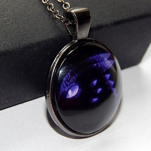May include: A black and purple dragon eye pendant necklace with a silver chain and a round glass cabochon.
