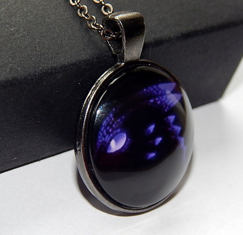 May include: A black and purple dragon eye pendant necklace with a silver chain and a round glass cabochon.