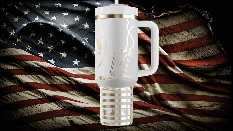 以下が含まれることがあります： ハンドル、ゴールドのアクセント、蓋が付いた白い断熱タンブラー。タンブラーには、ドッグタグと「Officer」の文字がデザインされています。背景はアメリカ国旗です。