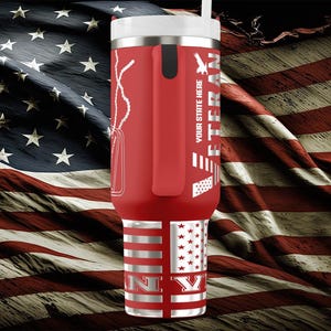 以下が含まれることがあります： 白い蓋とストローが付いた赤い断熱タンブラー。ドッグタグ、ワシ、そして「VETERAN」の文字がデザインされています。タンブラーの底には「NY」の文字が入った旗のデザインがあります。背景はアメリカ国旗です。