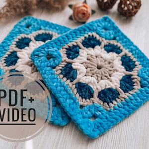 May include: Two square, crocheted coasters in shades of blue, white, and gray. The coasters feature a floral-like pattern in the center and are surrounded by a textured border. The text "PDF + VIDEO" is overlaid on the image.