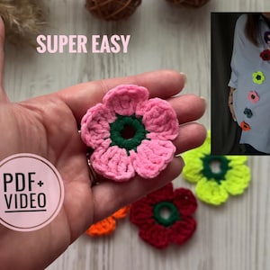 Könnte beinhalten: Nahaufnahme einer Hand, die eine gehäkelte rosa Blume mit grünem Zentrum hält. Weitere gehäkelte Blumen in verschiedenen Farben, darunter Rot, Gelb und Orange, sind darunter verstreut. Der Text "SUPER EASY" und "PDF + VIDEO" ist ebenfalls sichtbar.