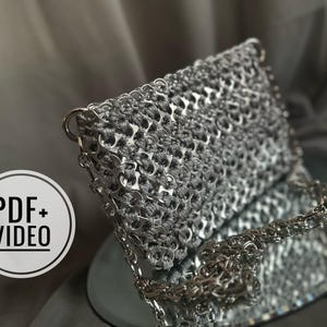 May include: A silver clutch bag made from recycled aluminum can tabs. The bag has a rectangular shape with a chain strap and a metallic sheen. The image also includes a "PDF + VIDEO" graphic.