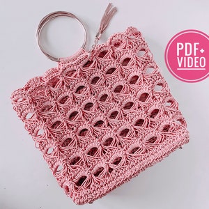 May include: A pink crocheted tote bag with a large, round, silver handle. The bag has a delicate, open-weave pattern and a tassel hanging from the handle. The text "PDF + VIDEO" is visible in the upper right corner of the image.