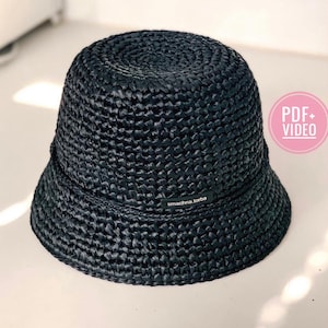 Pode incluir: Chapéu de balde tecido preto com uma aba larga e uma pequena etiqueta que diz "smachna.torba".