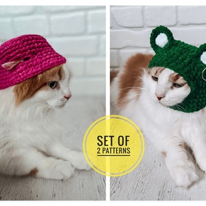 May include: Two crochet cat hats, one pink and one green. The pink hat is a bucket hat style and the green hat is a frog hat with white eyes. Both hats are on cats.