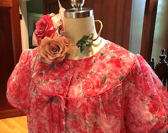 May include: A pink and white floral print robe with a tie at the waist and short sleeves. The robe is on a mannequin with a floral headpiece.