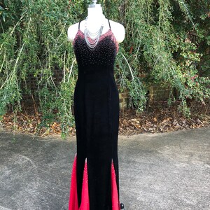 Puede incluir: Un vestido de noche de terciopelo negro con una superposici&oacute;n de gasa roja. El vestido presenta un corpi&ntilde;o con cuentas y una silueta ajustada.