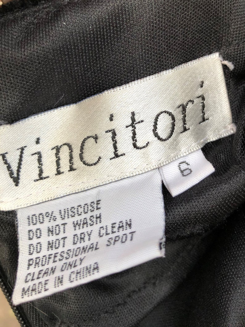 Puede incluir: Una etiqueta blanca con texto negro que dice "Vincitori" e instrucciones de cuidado para una prenda. La etiqueta dice "100% Viscosa", "No Lavar", "No Limpiar en Seco", "Limpieza en Seco Profesional", y "Hecho en China".