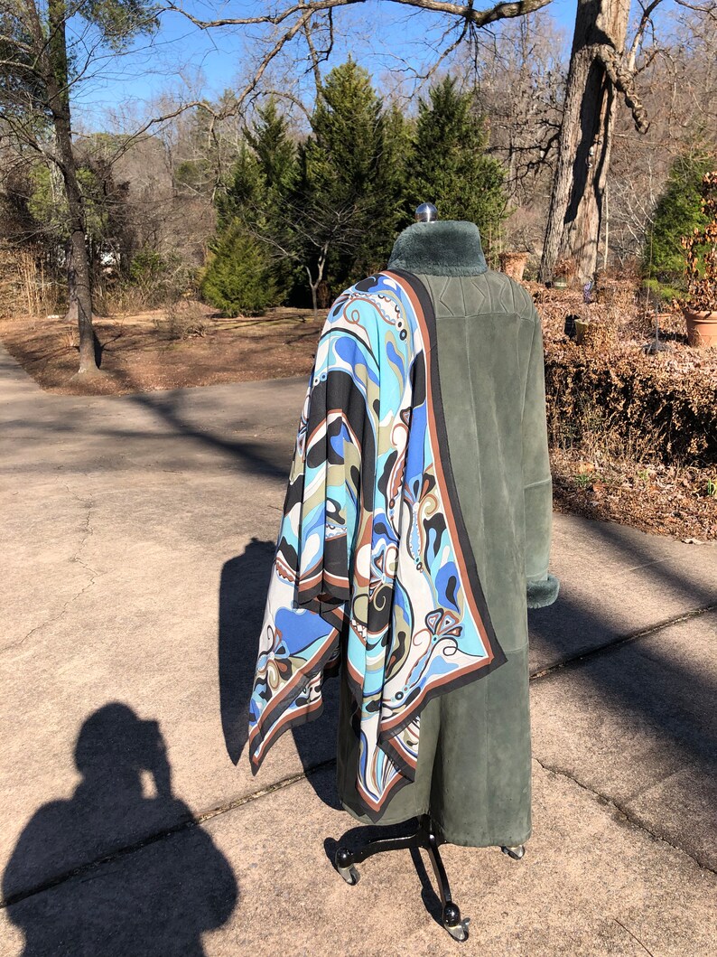 May include: A green suede coat with a fur collar and a blue, brown, and white patterned scarf draped over it.