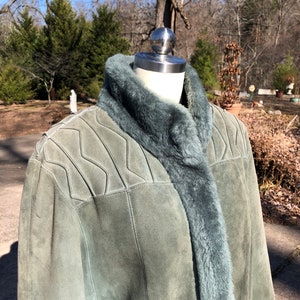 May include: A green suede jacket with a faux fur collar and lining. The jacket has a quilted design on the shoulders and a zipper closure.