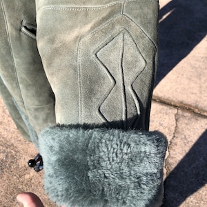 May include: A green suede jacket with a fur lining. The jacket has a diamond-shaped pattern on the elbow.