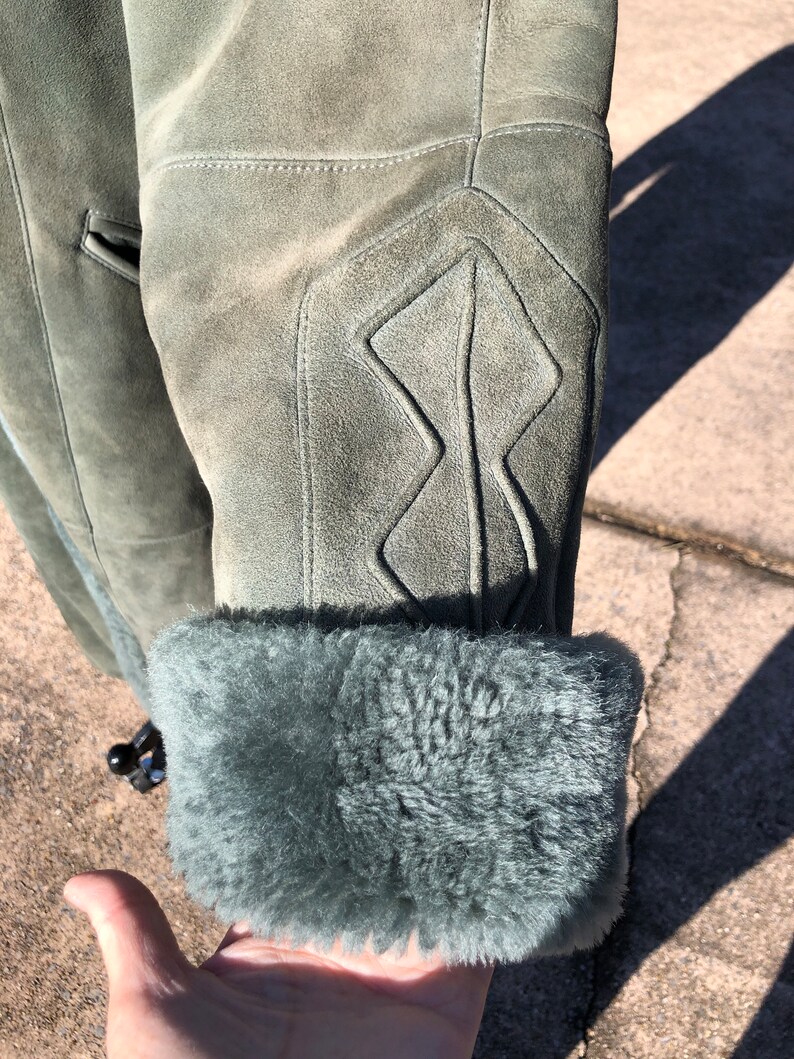 May include: A green suede jacket with a fur lining. The jacket has a diamond-shaped pattern on the elbow.