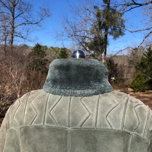 May include: A green suede jacket with a faux fur collar. The jacket has a quilted design on the back.