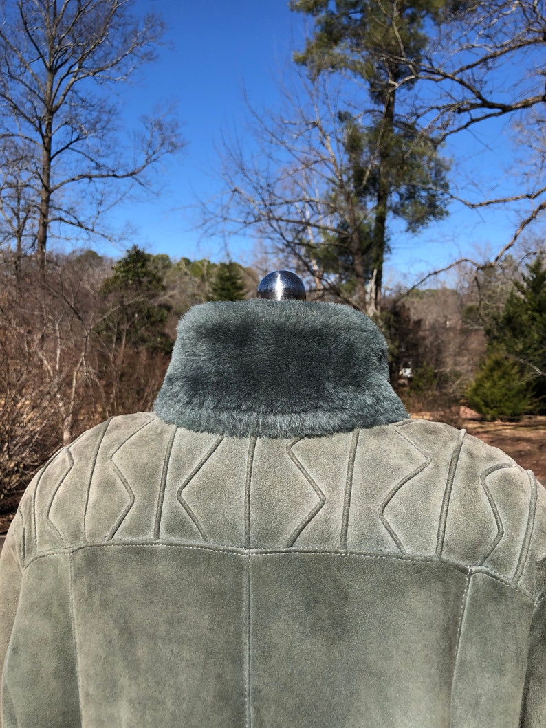 May include: A green suede jacket with a faux fur collar. The jacket has a quilted design on the back.