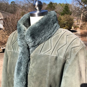May include: A green suede jacket with a shearling collar. The jacket has a zipper closure and a quilted design on the shoulders.