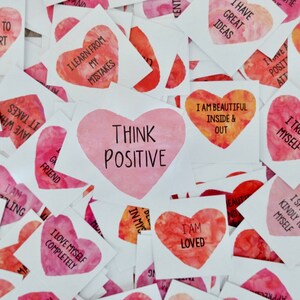 May include: A collection of pink and red heart-shaped stickers with positive affirmations printed on them. The stickers have watercolor-like designs and include phrases like "Think Positive", "I Love Myself Completely", and "I Trust Myself".