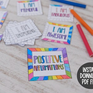 Op de afbeelding: Een set printbare positieve affirmatiecards met een regenboogrand. De kaarten bevatten zinnen als "Ik ben geliefd", "Ik ben aandachtig", "Ik ben inspirerend", "Ik ben geweldig" en "Ik ben fantastisch". De kaarten zijn klaar om te worden afgedrukt en ingekleurd.