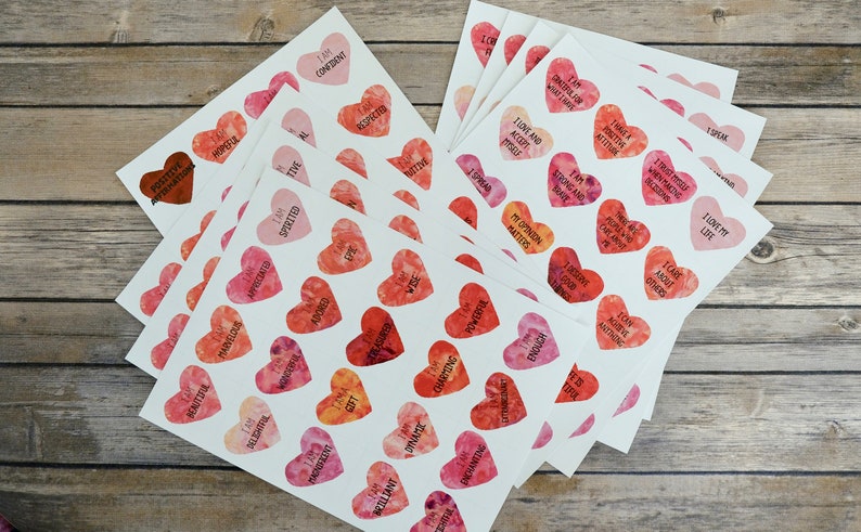 May include: A stack of white cards with watercolor hearts printed on them. Each heart has a positive affirmation printed on it, such as "I am confident", "I love my life", and "I am spirited".