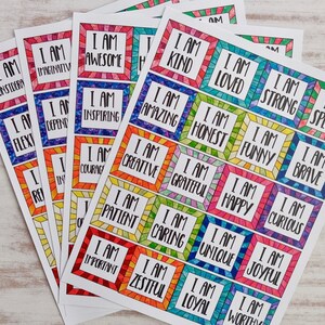 Op de afbeelding: Een set kleurrijke affirmatiecards met positieve boodschappen zoals "Ik ben geweldig", "Ik ben aardig" en "Ik ben creatief". De kaarten zijn gedrukt op wit papier en hebben een regenboogkleurige rand.